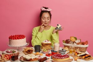 pleased brunette woman holds small creamy muffin bakes many desserts new year holiday festive time demonstrates her culinary abilities